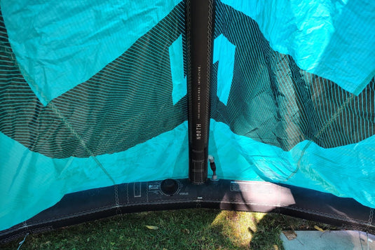 Green Hat Kiteboarding-2024 9m North Reach Kite-Close Up View of Valve & Center Strut View of Turquoise kite with 'North' branding on a grassy area