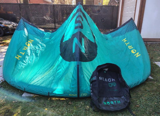 Green Hat Kiteboarding-2024 9m North Reach Kite-Turquoise kite with 'North' branding on a grassy area with Bag