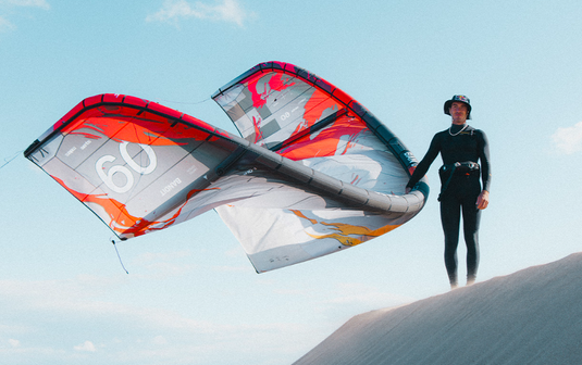 Green Hat Kiteboarding-2025 F-One Bandit Limited Edition by Brianchild Kite-Live Shot-Man Standing on Top of a Dune Holding the Bandit by Brainchild