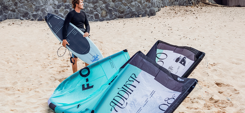 Load image into Gallery viewer, Green Hat Kiteboarding-2025_F-One_Addikt_Kite-Black/Mint-F-One Kite on the Beach next to Pro Rider Keahi holding an F-One Kite Surfboard
