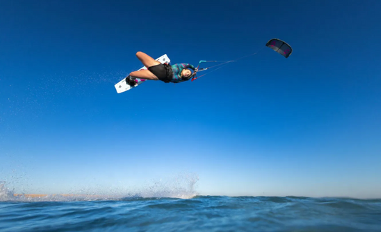 Green Hat Kiteboarding-2026 Duotone Concept Blue Kiteboard-Action Shot-Woman Doing an Unhooked Trick on a Soleil Twintip