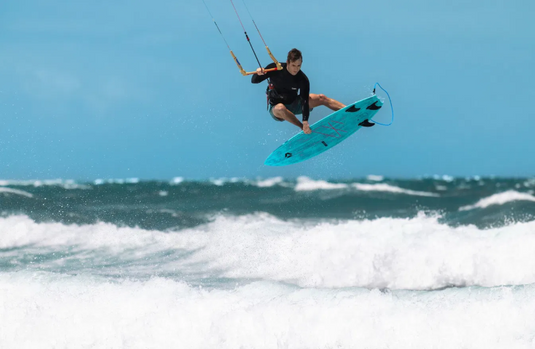 Green Hat Kiteboarding-2026 Duotone Volt SLS-Action Shot-Man Doing an Air on a Volt SLS surfboard