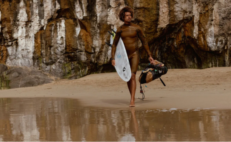 Load image into Gallery viewer, Green Hat Kiteboarding-2026 Duotone Whip D/Lab Surfboard-Live Shot-Man Walking on the Beach Wearing a Wetsuit Carrying A Whip D/Lab
