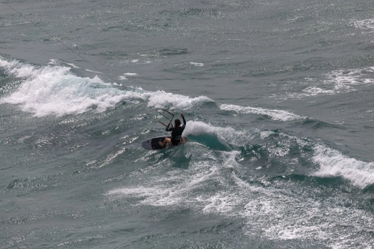 Green Hat Kiteboarding-2026 Duotone Whip D/Lab Surfboard-Action Shot-Man Kitesurfing with the Whip D\Lab on a Wave
