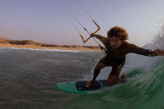 Green Hat Kiteboarding-2026 Duotone SLS Surfboard-Action Shot-Man Kitesurfing a Wave on a Whip SLS