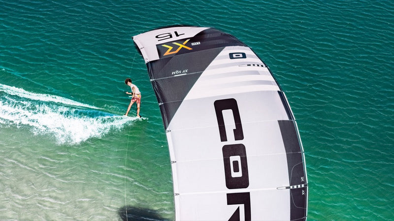 Load image into Gallery viewer, A person riding the Core XR7 7m Kiteboarding Kite USED on a surfboard, enjoying windsports and surface water sports.
