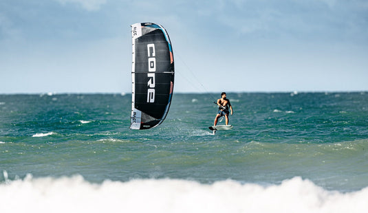 Green Hat Kiteboarding-Core Pace White Color-Action Shot-Man Kite Foiling on Black Pace Kite