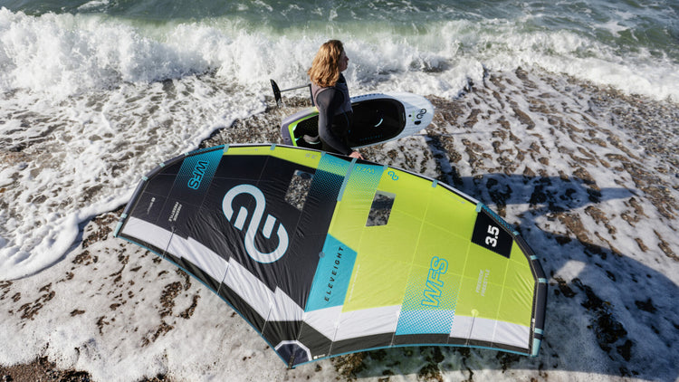 Green Hat Kiteboarding-Eleveight WFS V6-Live Shot-Man Walking on the Beach with his Eleveight Gear in Hand