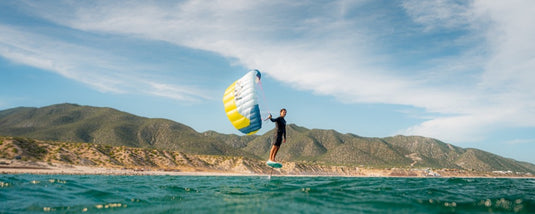 Person parawinging with a  Flysurfer POW2  parawing on a body of water with mountains in the background