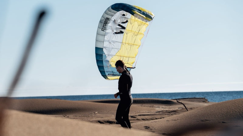 Load image into Gallery viewer, Person on a beach with Flysurfer POW2  parawing in the background
