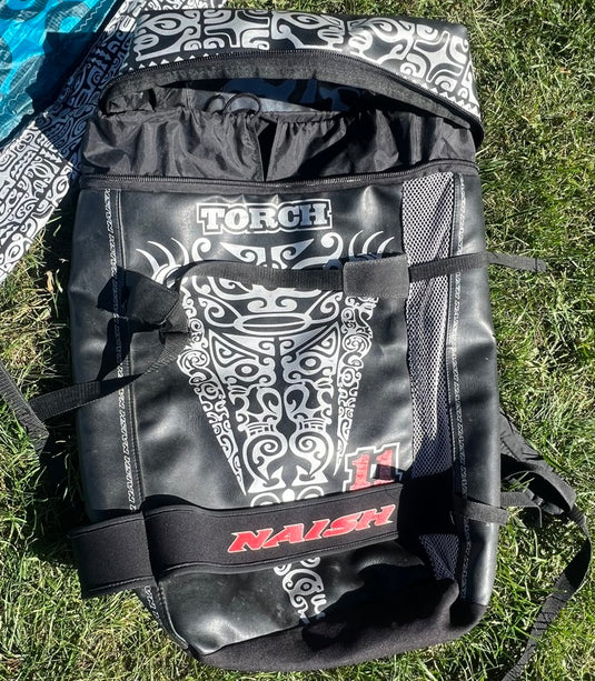 2011 Naish Torch 11m Kiteboarding Kite: A kiteboarding kite totebag with a white design on it, lying on grass.