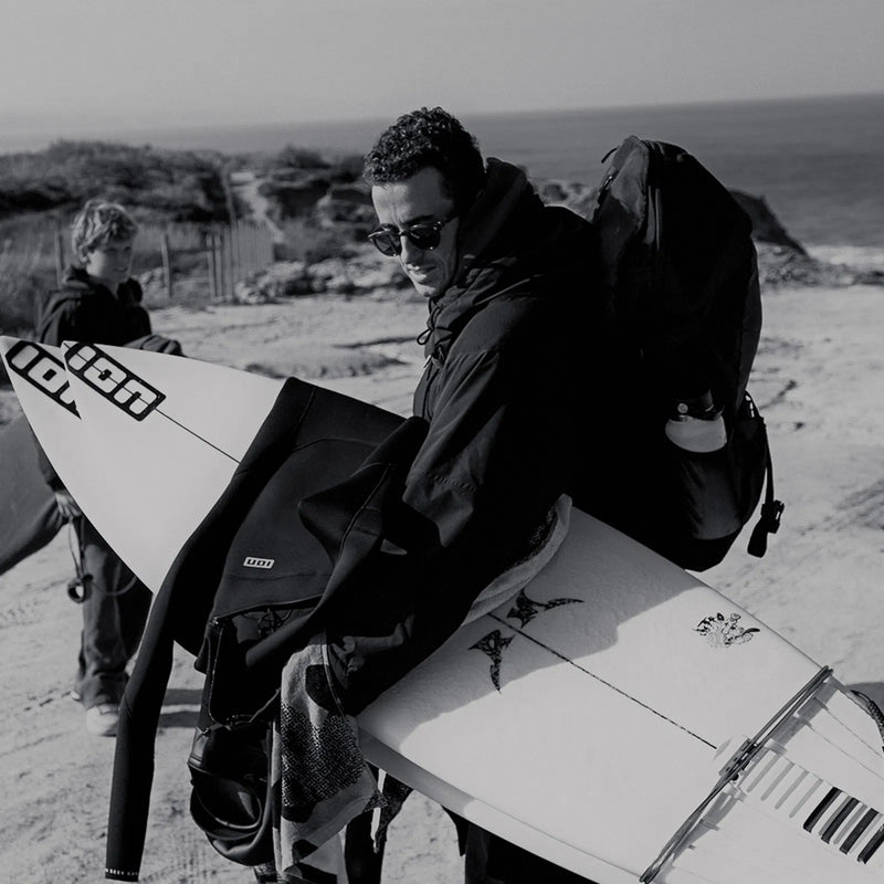 Load image into Gallery viewer, Green Hat Kiteboarding-ION Mission Pack-Black-Live Shot-Man Walking on the Beach with ION Mission Pack
