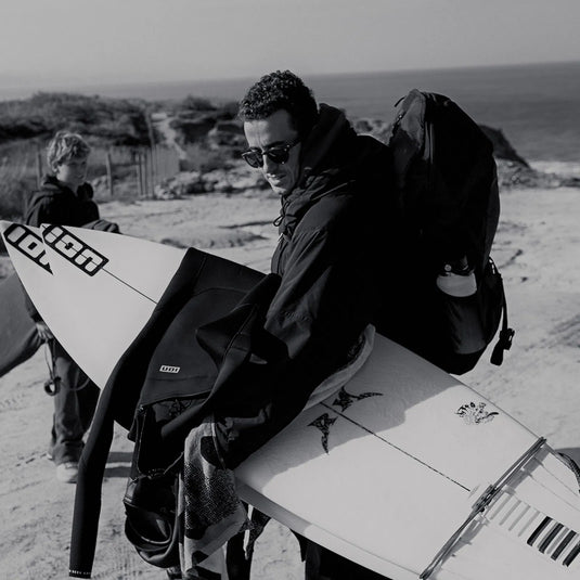 Green Hat Kiteboarding-ION Mission Pack-Black-Live Shot-Man Walking on the Beach with ION Mission Pack