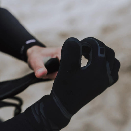 Person wearing black Ion pre-curved gloves holding a black object against a blurred background