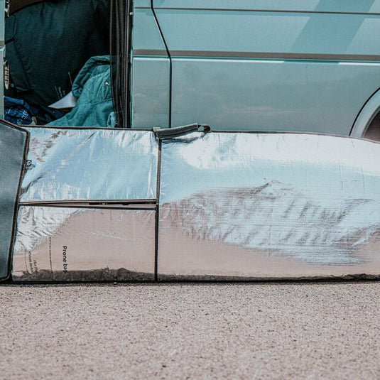 Green Hat Kiteboarding-Manera Prone Foilboard Bag-Close-up of bottom reflective surface of Manera Prone Bag Leaning on a Van on pavement