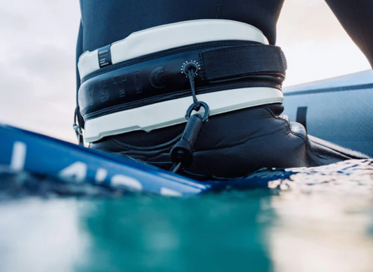 Green Hat Kiteboarding-Mystic Stage Wing Harness-Live Shot-Man Sitting on a Board in the Water Wearing Stage Harness