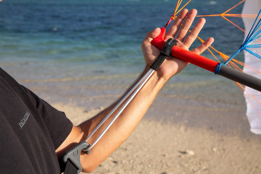 Green Hat Kiteboarding-Ozone Wing/Parawing Harness Line-Man holding a parawing bar with a harness line with a beach and ocean in the background