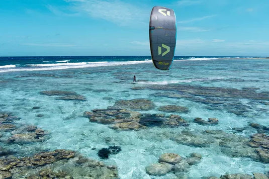 Green Hat Kiteboarding-2026 Duotone EVO DLAB-Dark Grey/Lime-Action Shot-Person kiteboarding over clear blue water with a coral reef