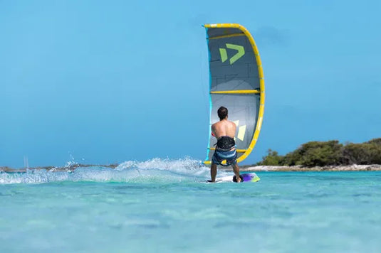 Green Hat Kiteboarding-2026 Duotone EVO DLAB-Dark Grey/Lime-Action Shot-Man kiting on a clear blue ocean with a Duotone Evo DLAB